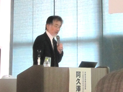 演台でノートパソコンに目をやりながら話をする阿久澤委員の写真