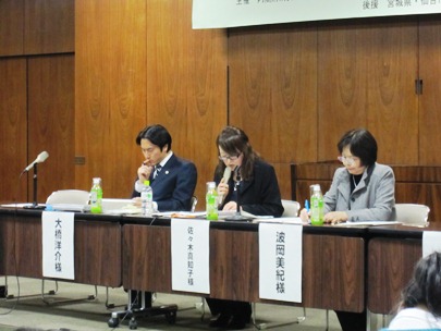 事例報告者３名が着席し、中央の佐々木副支部長がマイクを持って報告している写真