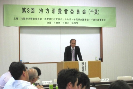 「第3回地方消費者委員会（千葉）」の横断幕を背に話をする河上委員長の写真